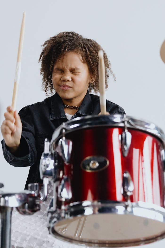 Child playing drums with eyes closed, showcasing musical talent and focus.